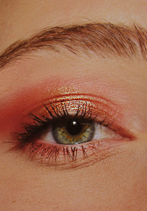 Load image 1 in gallery view. Close-up of a model's eye with pink/red metallic eyeshadow and black mascara.