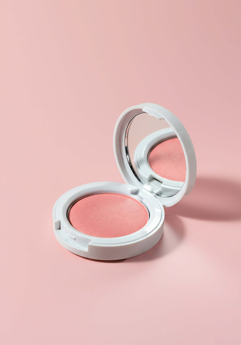 A peachy blush in a round white plastic compact.