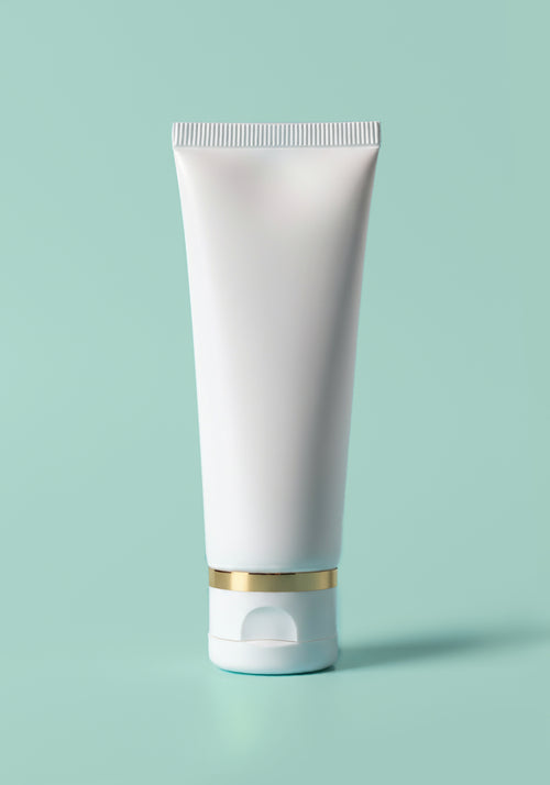 Load image 1 in gallery view. A white tube stored on its cap with a gold accented rim.